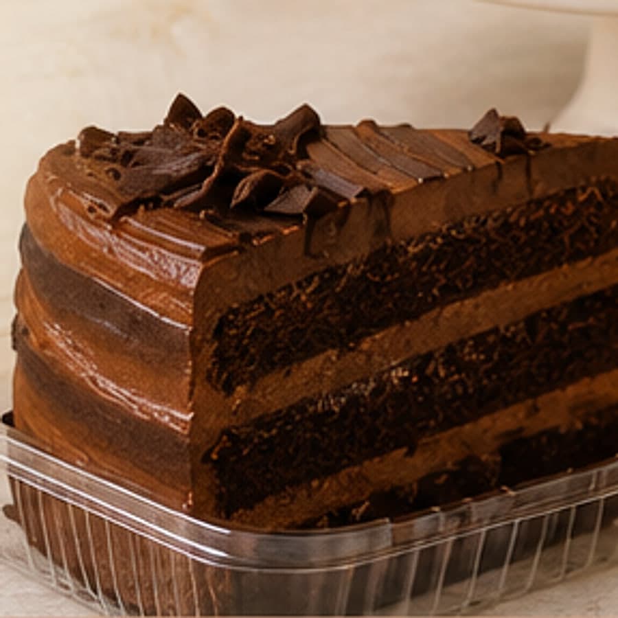 Porción de torta de chocolate de tres capas con cobertura y virutas, en empaque individual